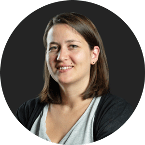 Porträt einer lächelnden Frau mit braunen schulterlangen Haaren vor einem dunklen Hintergrund.