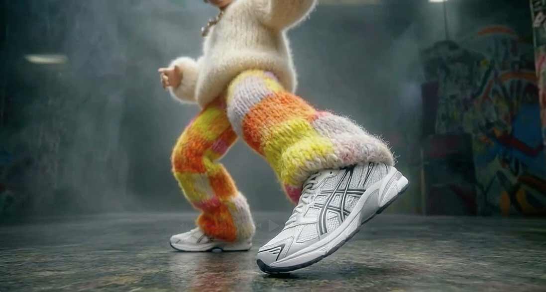 Nahaufnahme einer Person mit bunten, gestrickten Hosen und weißen Sportschuhen in Bewegung.