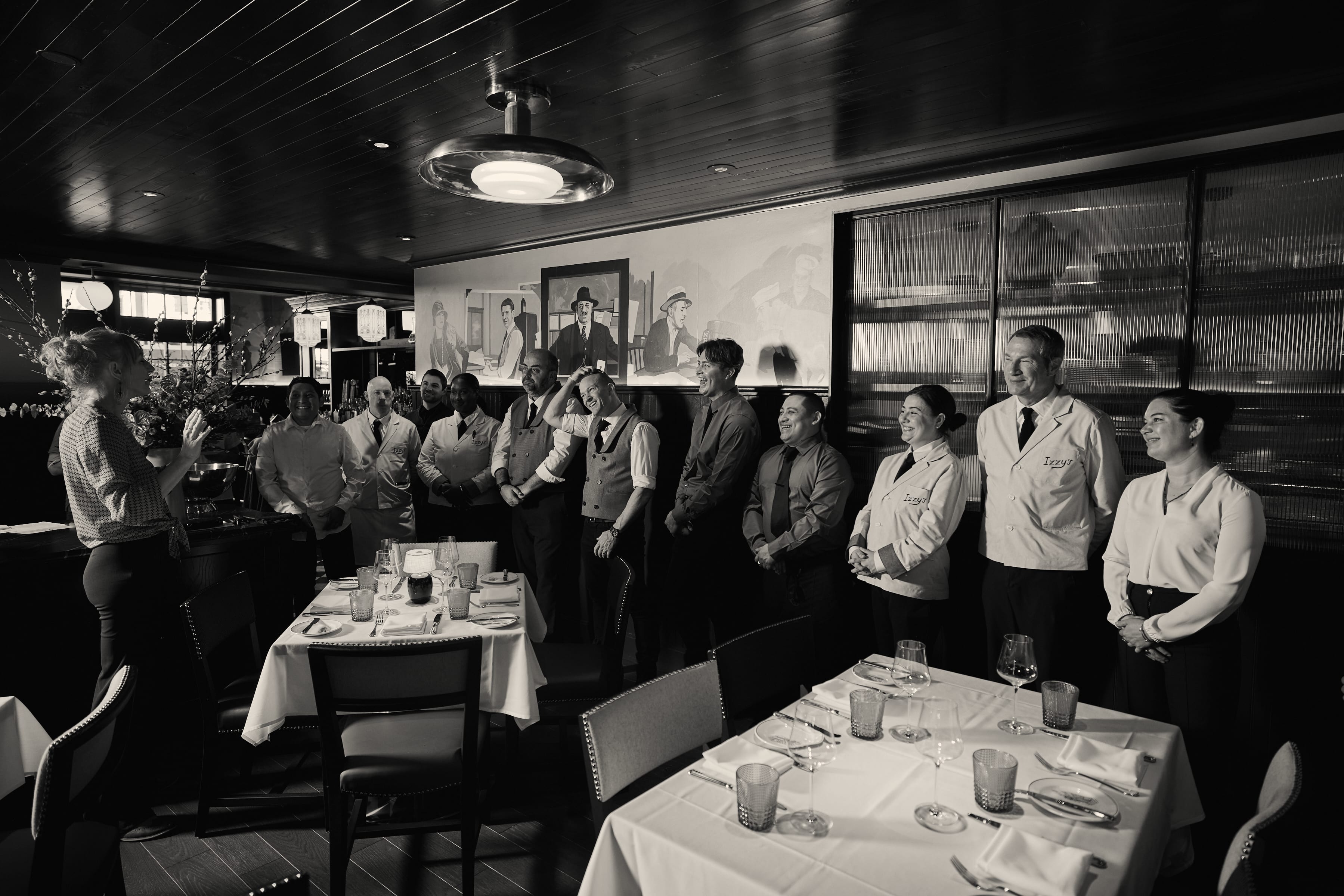 Black and white photo of Izzy's Steaks & Chops staff posed in the dining room