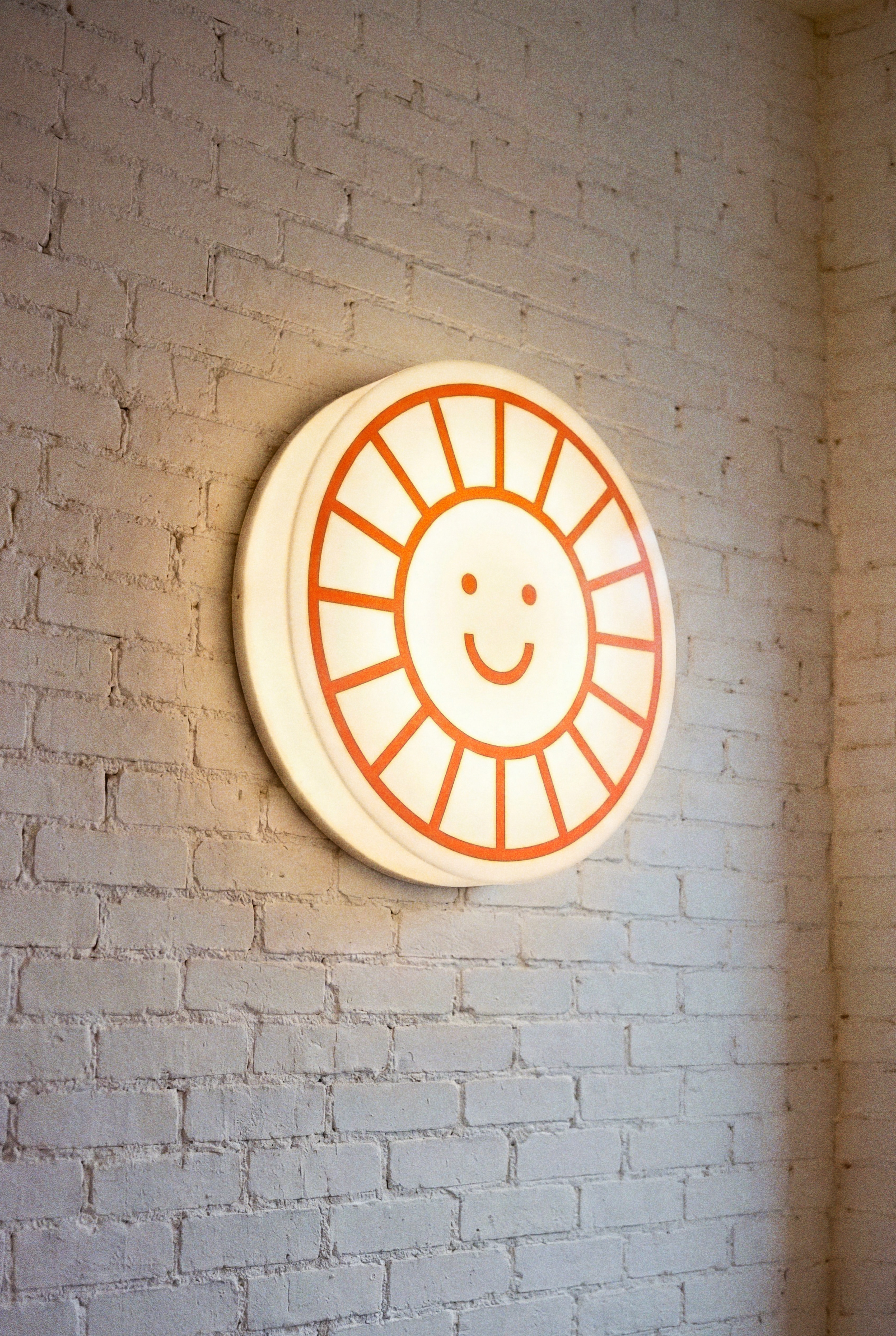 Illuminated Daypass sun logo sign mounted on a brick wall at night