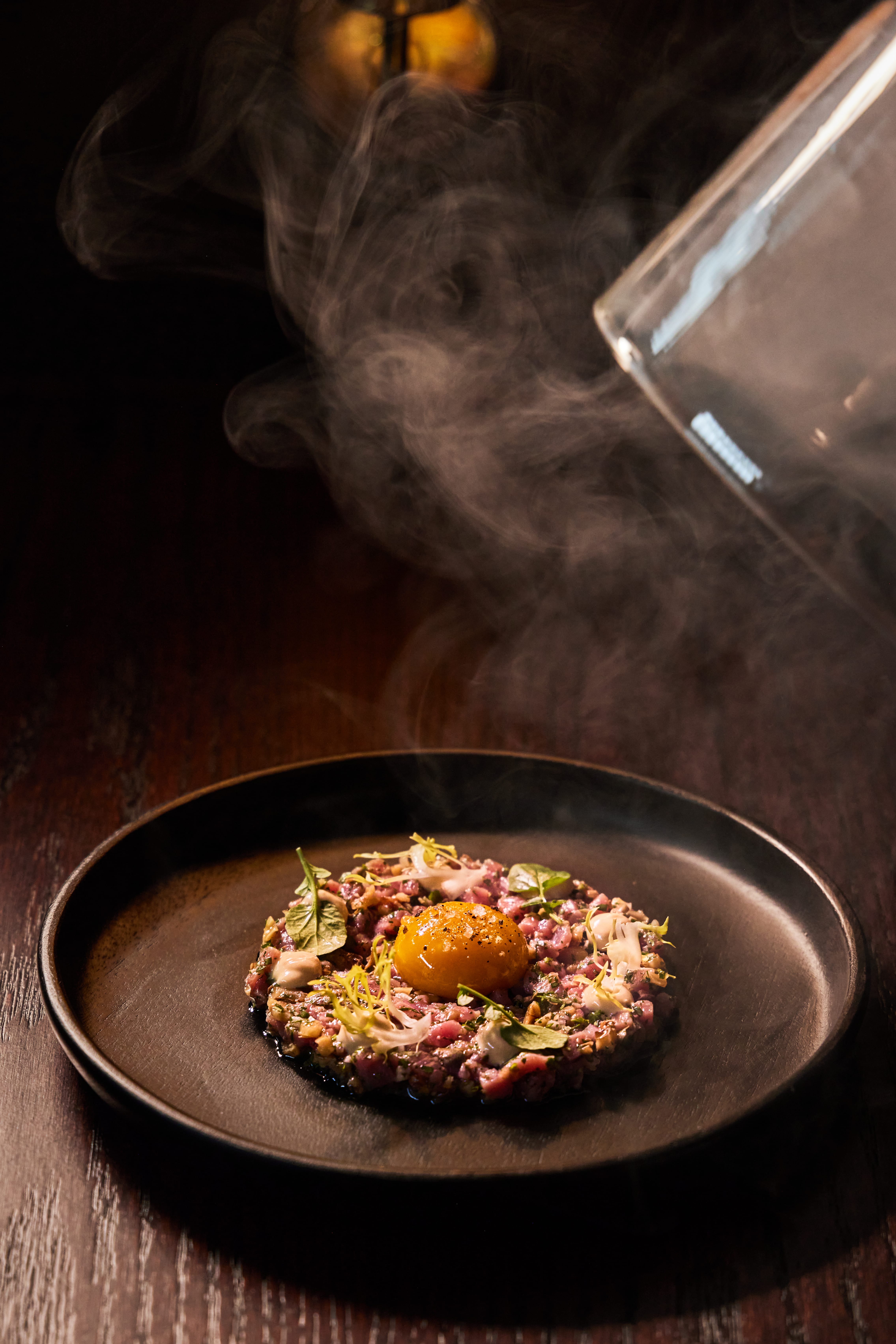 Veal tartare with steam rising, plated on Izzy's branded dishware