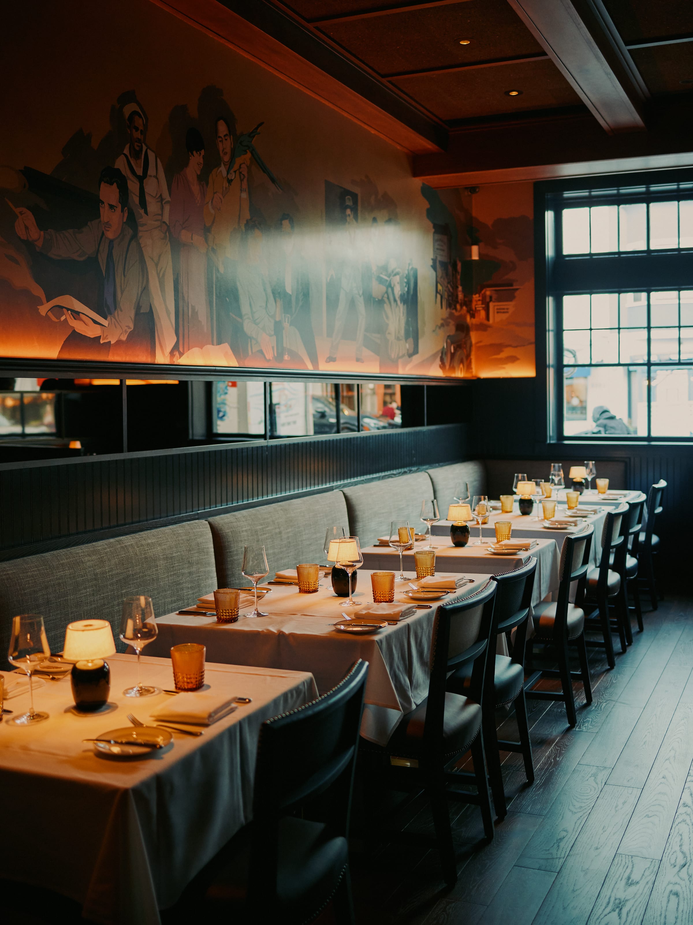 Candlelit banquette seating area with mural at Izzy's Steaks & Chops