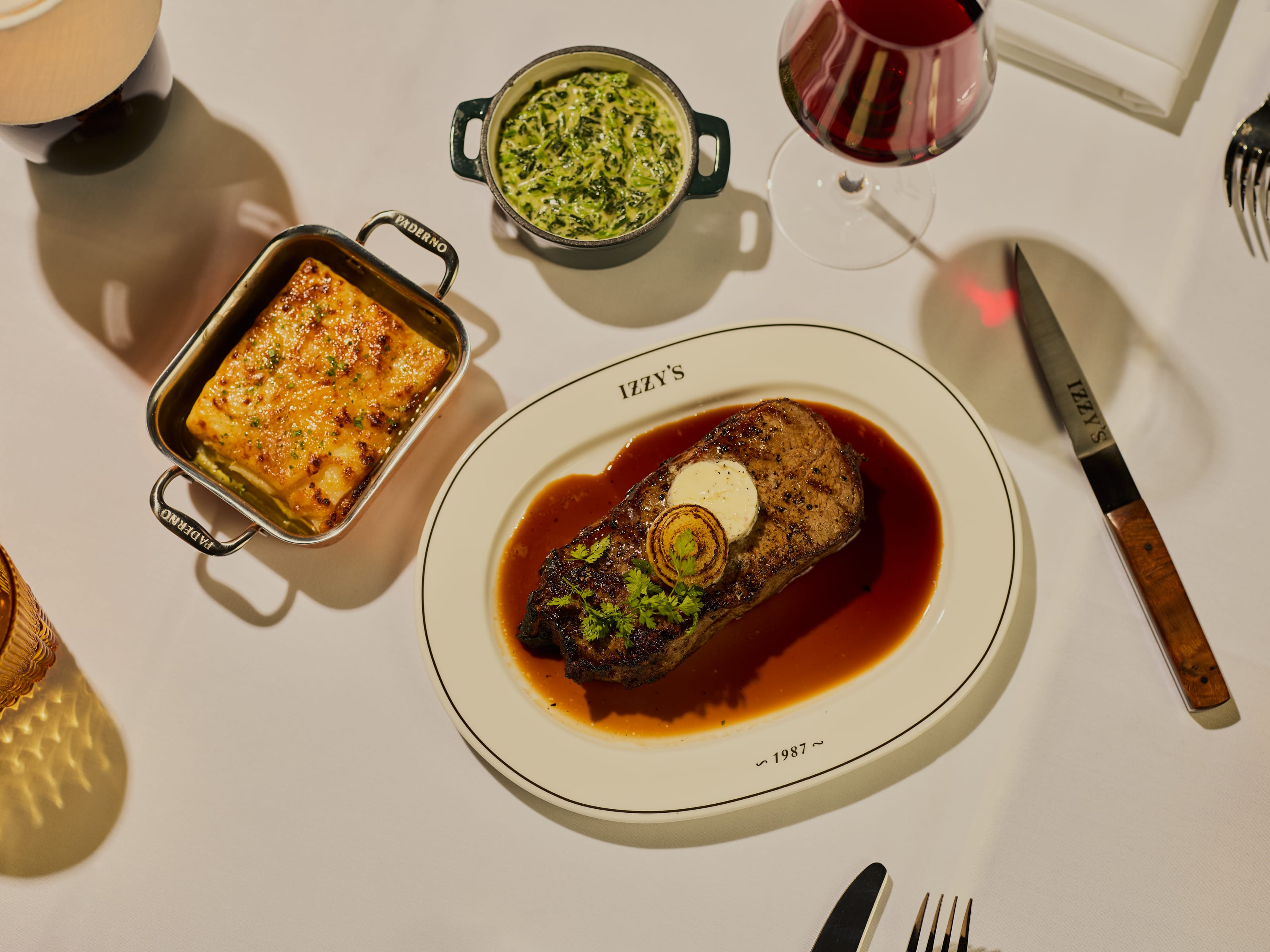 Overhead shot of a steak with red wine and sides at Izzy's