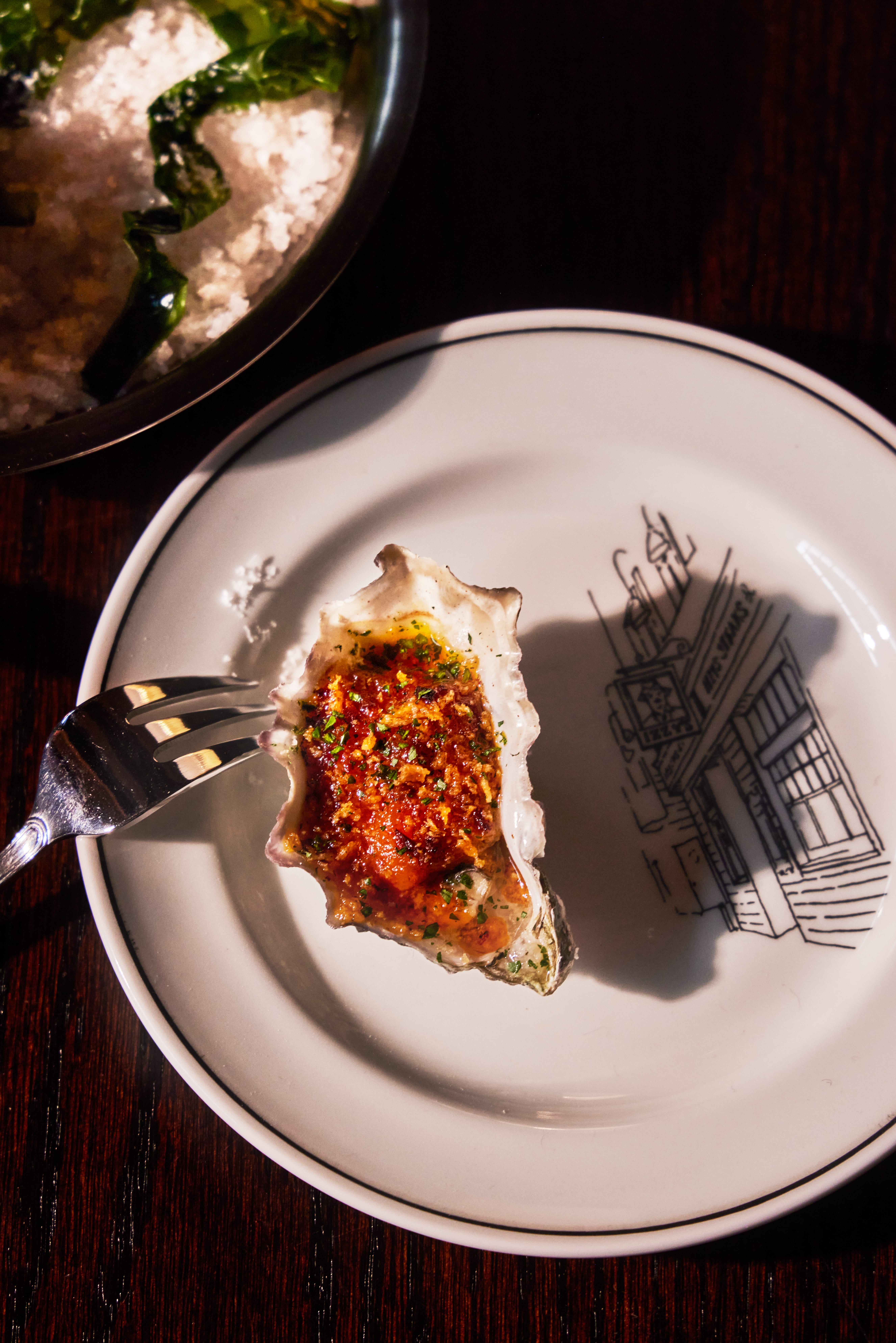 Oyster on an Izzy's branded plate featuring the restaurant building illustration