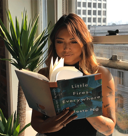 Animated GIF of woman holding 'Little Fires Everywhere' by Celeste Ng near a sunlit window