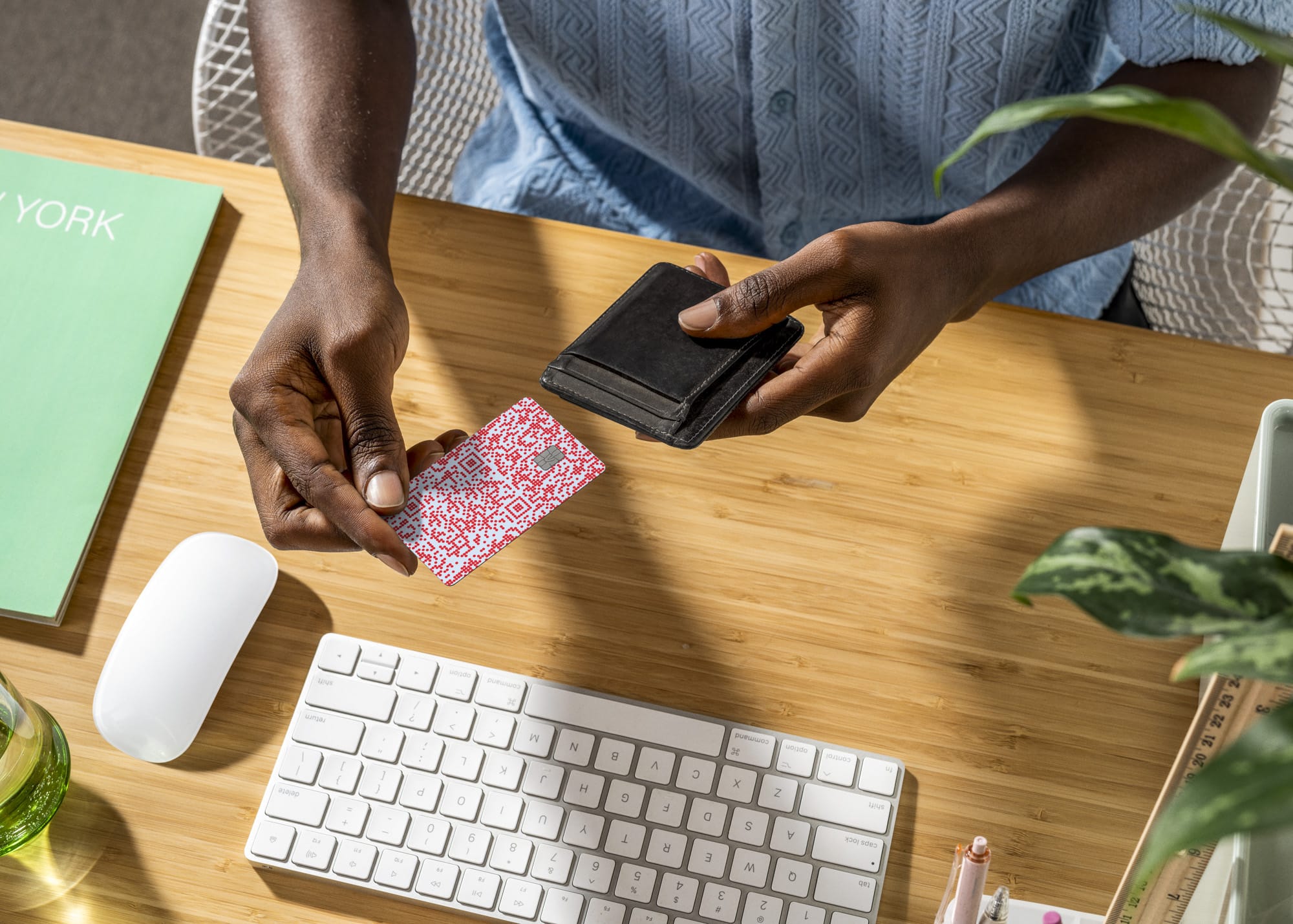 Overhead view of person at a bamboo desk pulling a colorful Venmo card from a slim black card holder
