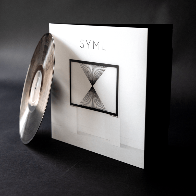 SYML album box set — black square packaging with silver vinyl record beside it and a small string art image printed on the box face