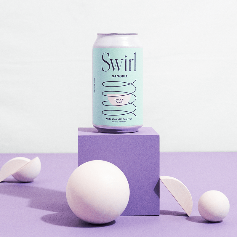 Single Swirl Sangria Citrus and Peach mint-green can on a purple lavender surface with white spheres
