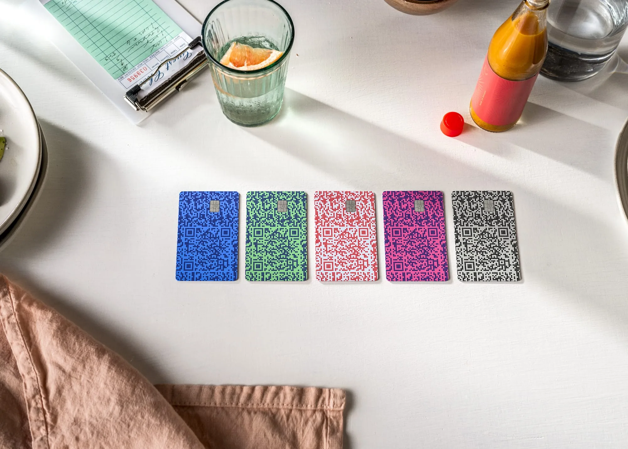 Five Venmo cards in different QR-code color patterns — blue, green, red, pink, black — laid out side by side on a restaurant table