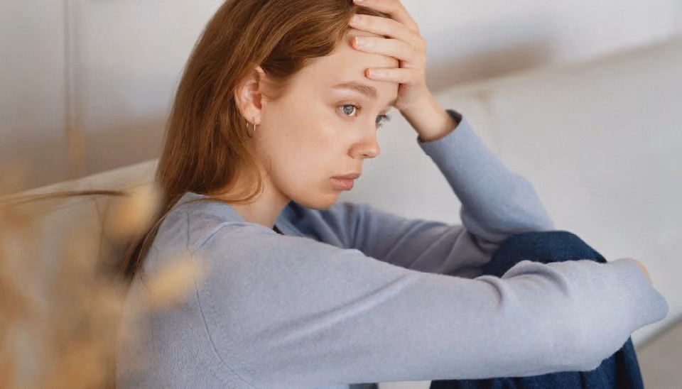Femme se tenant le front, l'air inquiète, ce qui illustre l'absence de règles caractéristique de l'aménorrhée