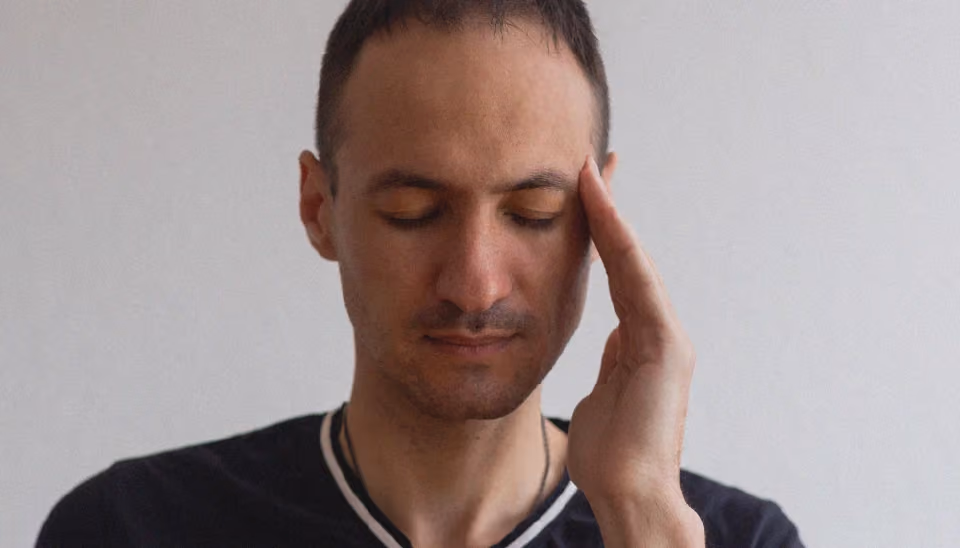 Une personne qui se tient la tête car elle a des migraines dues à son anémie.