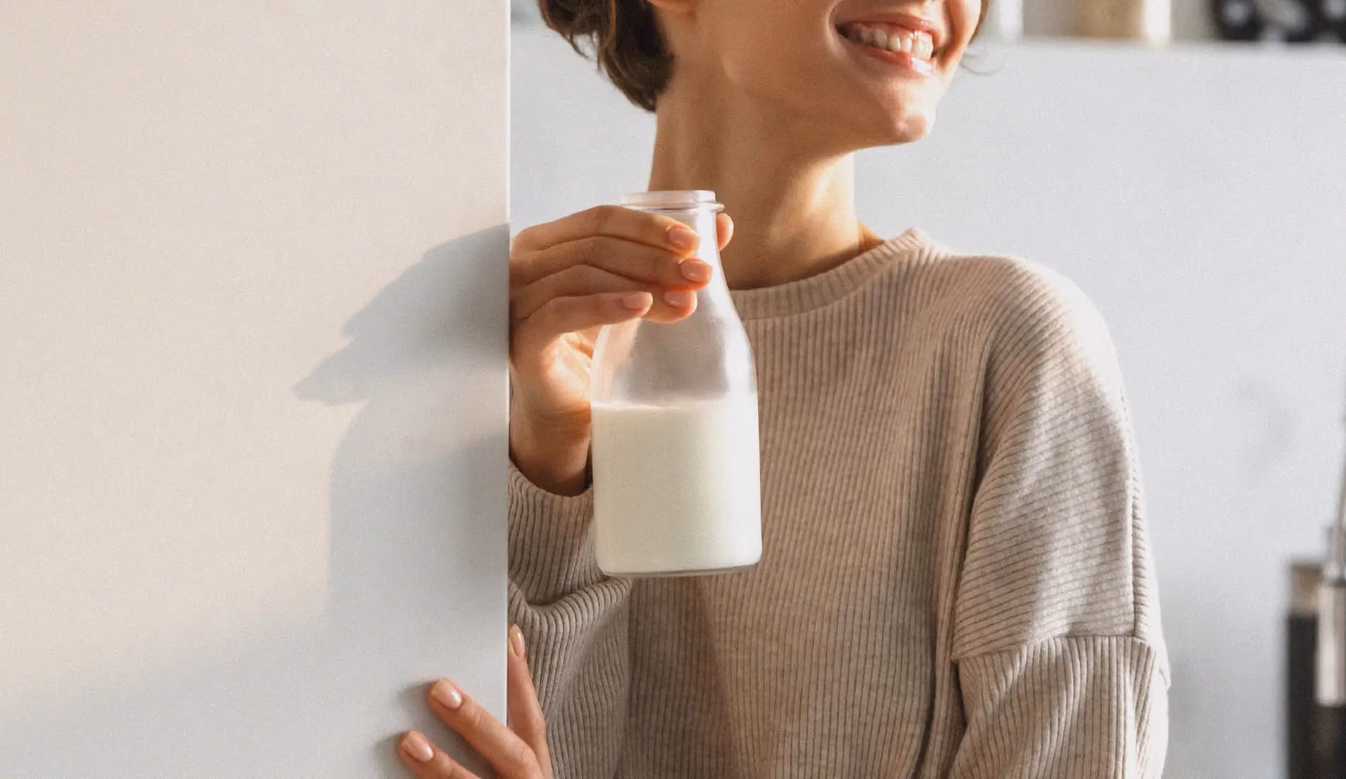 Une personne ouvre un frigo et en sort une bouteille de lait à moitié pleine