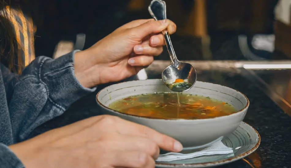 Une personne qui mange une soupe de légumes, car souffrant de gastro-entérite.