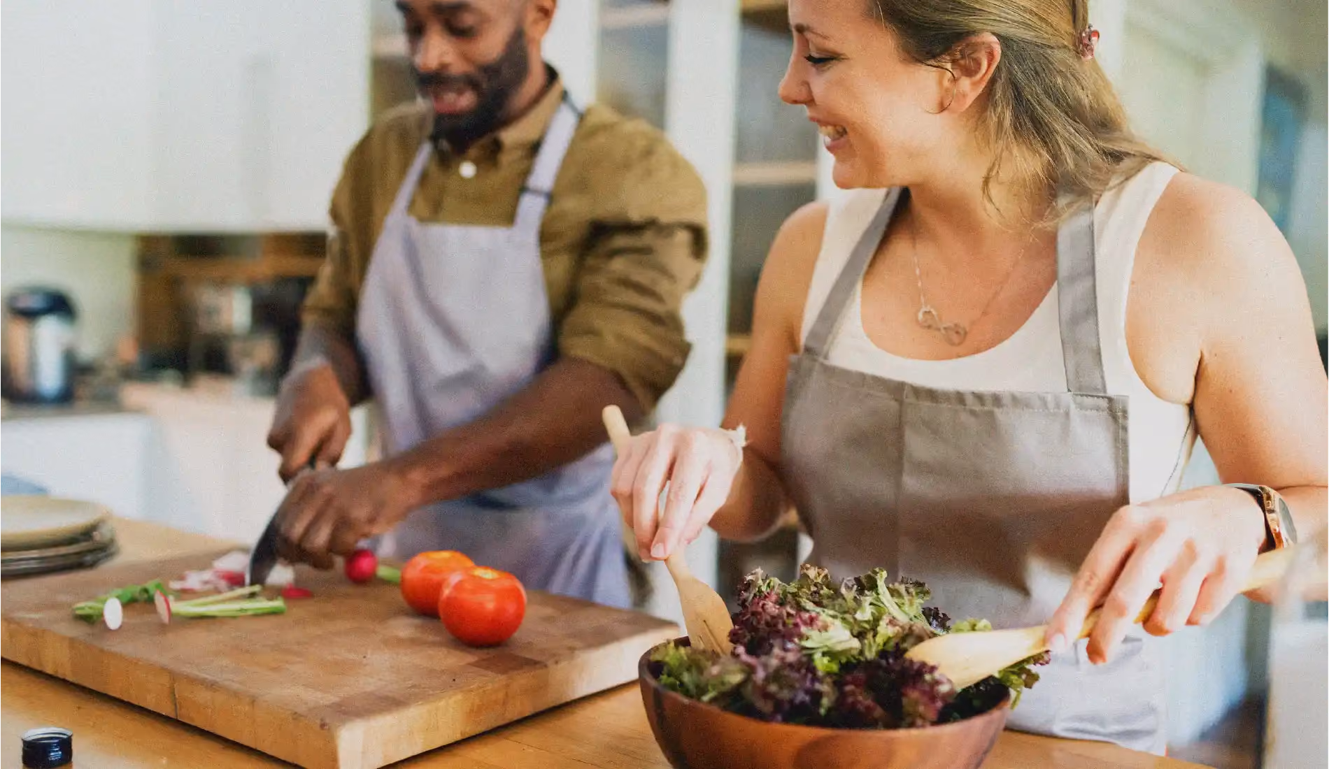 Un homme et une femme qui portent des tabliers et qui cuisinent des légumes afin de faire baisser leurs triglycérides.