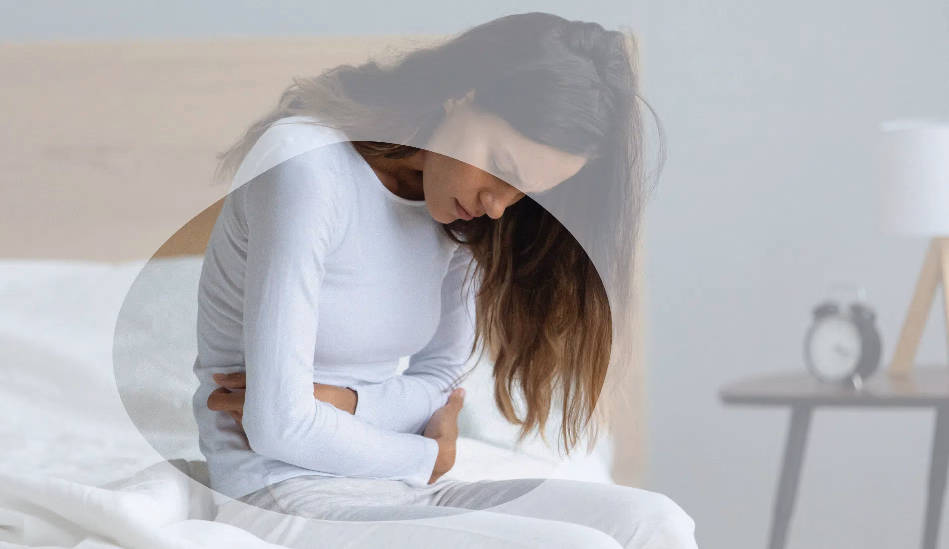 Une femme assise au bord de son lit et qui replie son bras droit douloureux.