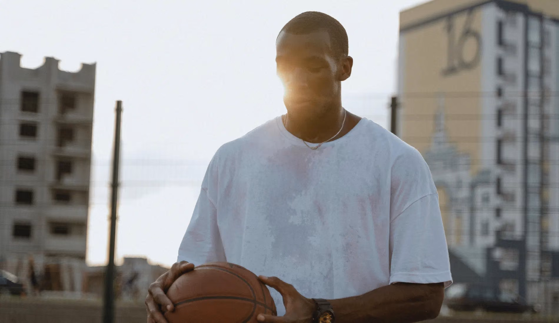 Un jeune homme qui tient un ballon de basket en main et qui transpire beaucoup.