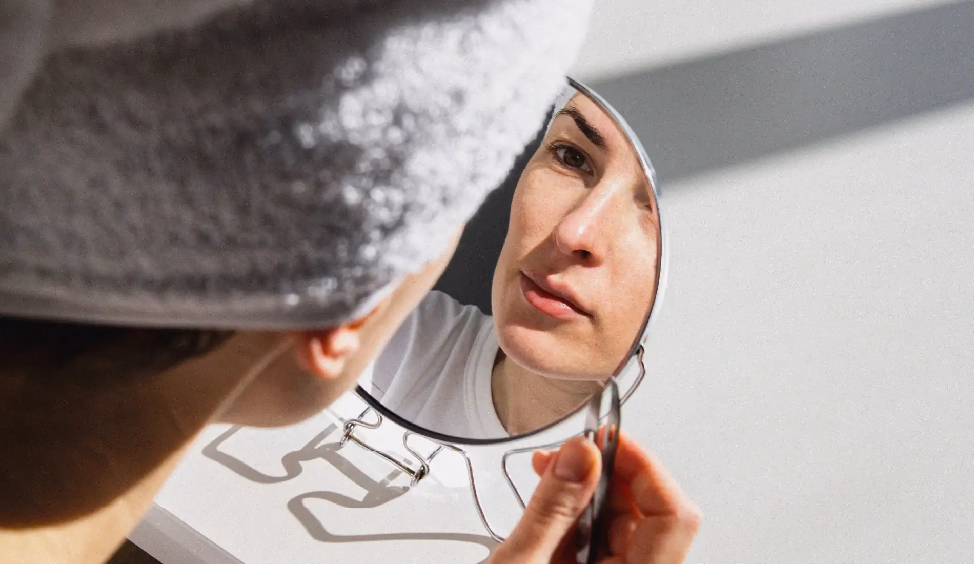 Une jeune dame avec un taux de cortisol élevé se tient debout, un miroir dans ses mains.