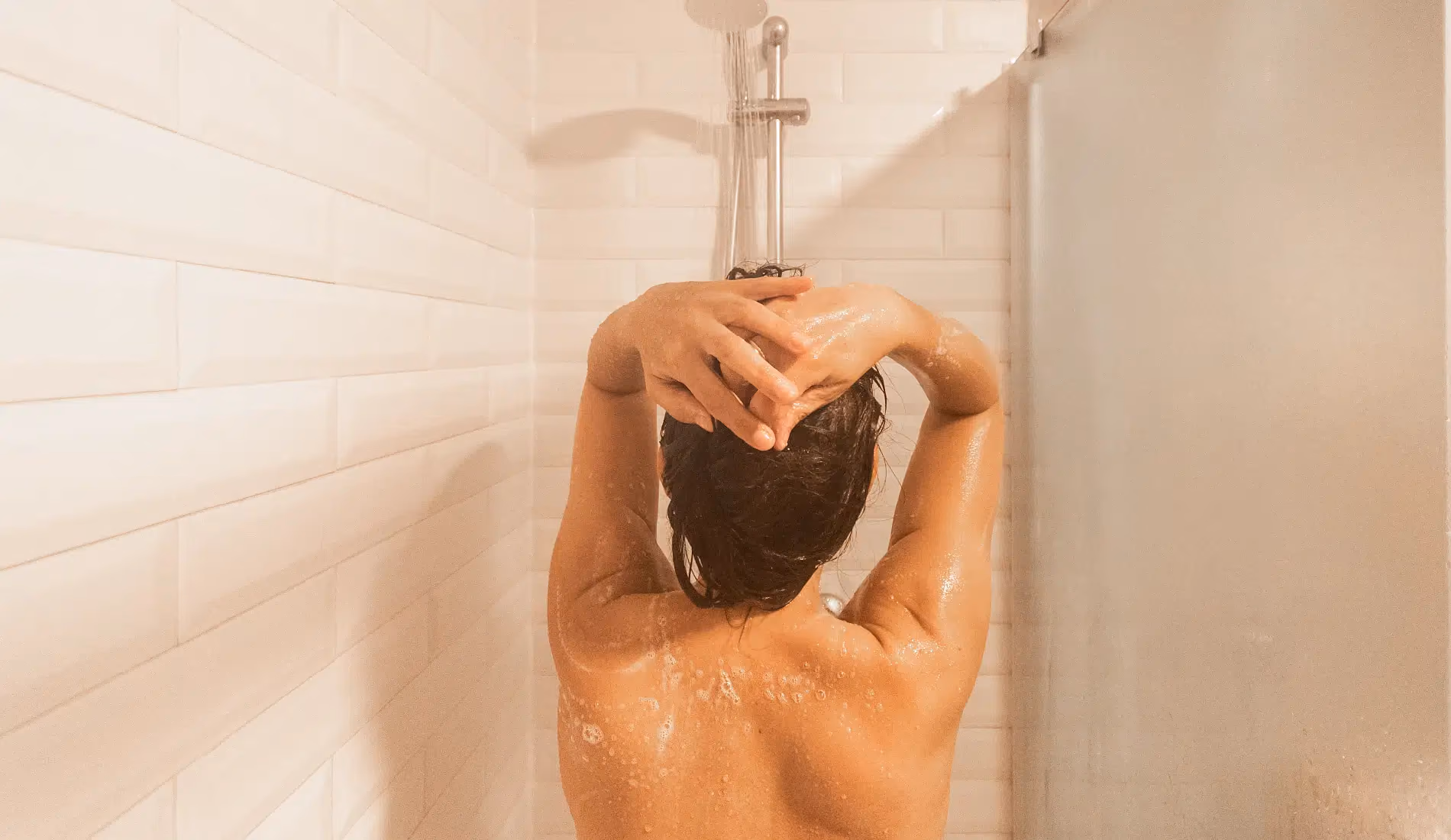 Une femme de dos, qui prend une douche car elle souffre de mauvaise odeur intime.