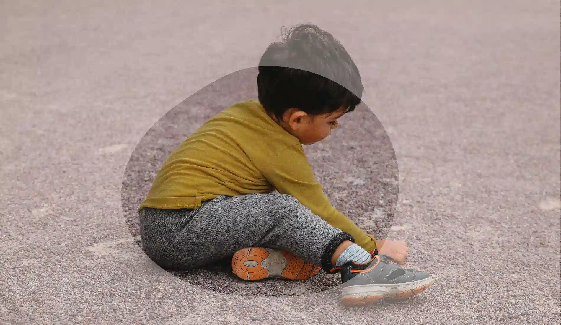 Un enfant en train de jouer, assis par terre.
