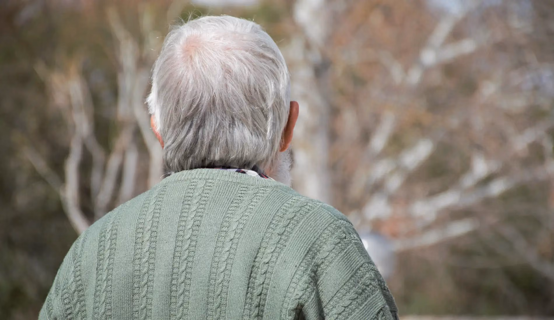 Une personne âgée qui tourne le dos à l'objectif, signe de l'ostéoporose.