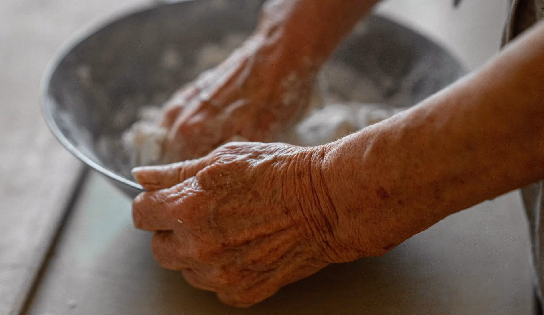 Les mains d'une personne âgée qui lave une assiette.