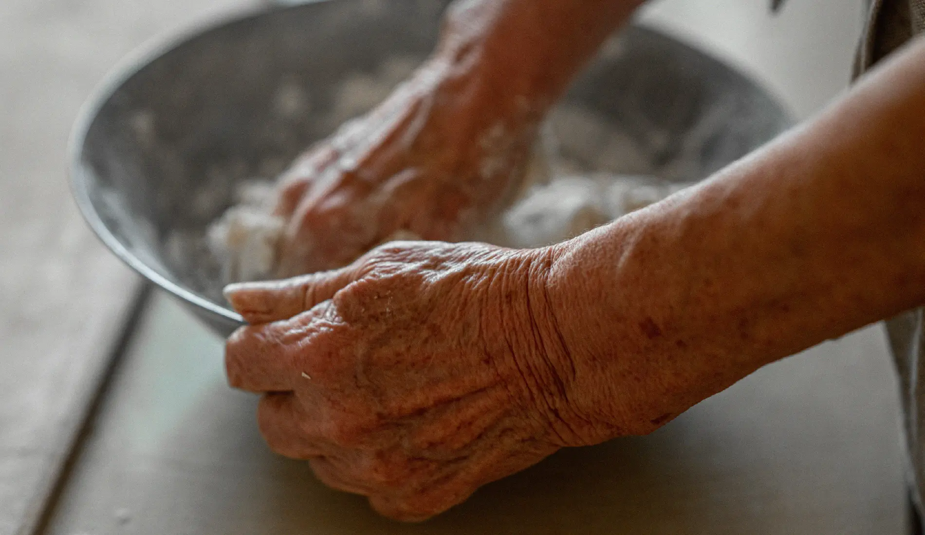 Les mains d'une personne âgée qui lave une assiette.