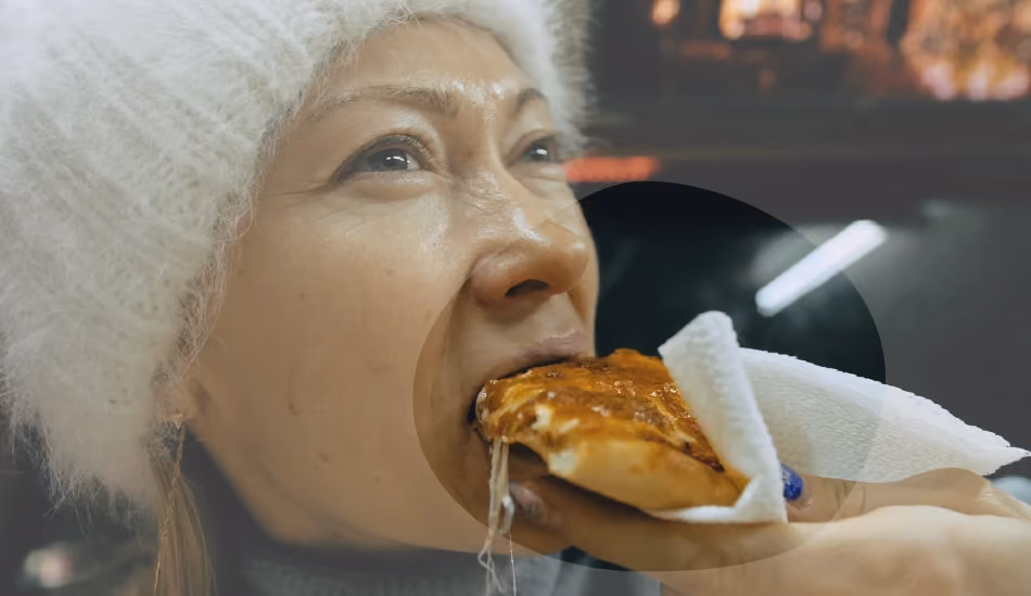 Une dame qui mange une part de pizza pour illustrer cet article sur l'ostéoporose.