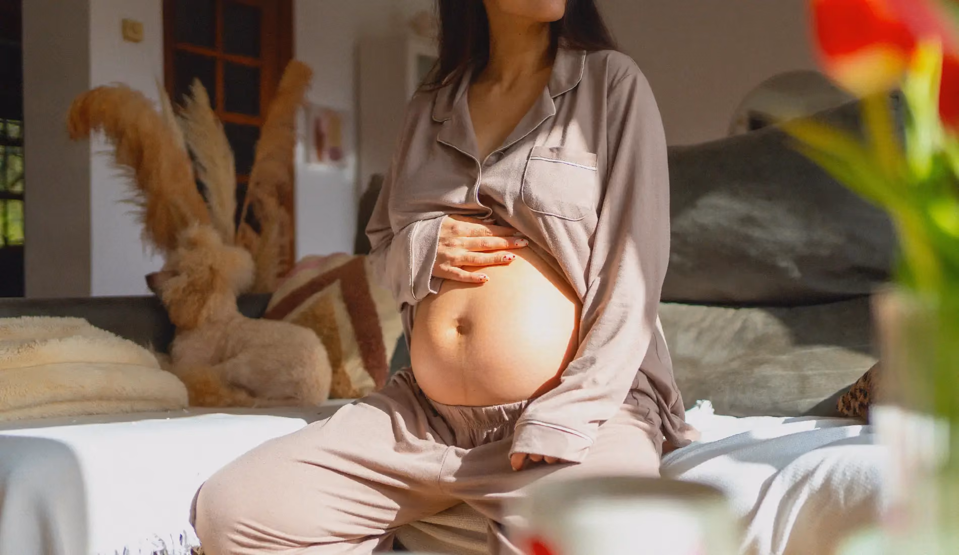 Une femme enceinte assise dans son lit, en train de se demander s'il est prudent d'avoir des rapports sexuels pendant la grossesse.