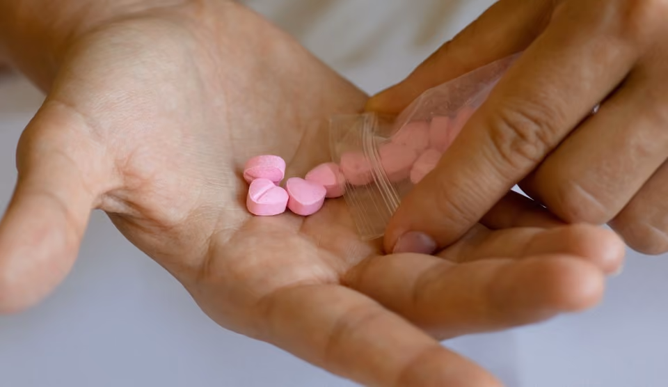 Une main tenant des comprimés de MDMA