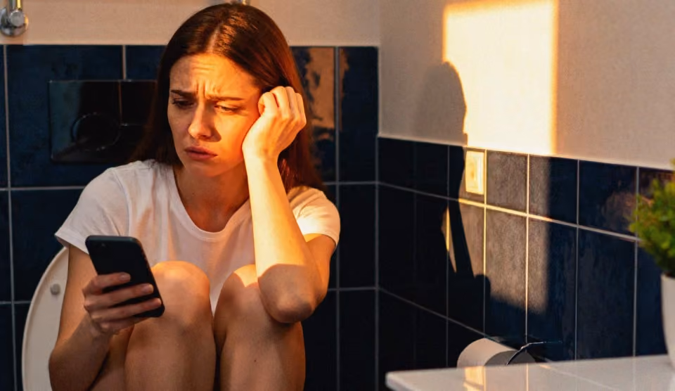 Une jeune femme triste, en train de faire des recherches sur les règles irrégulières, sur son téléphone.