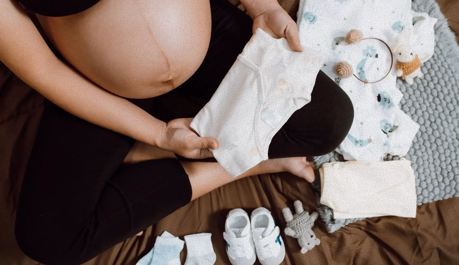 Une femme enceinte (grossesse), atteinte de SOPK, en train de toucher les vêtements de son bébé.
