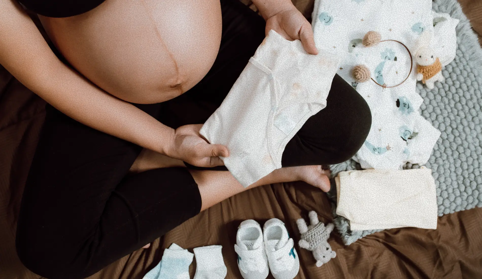 Une femme enceinte (grossesse), atteinte de SOPK, en train de toucher les vêtements de son bébé.