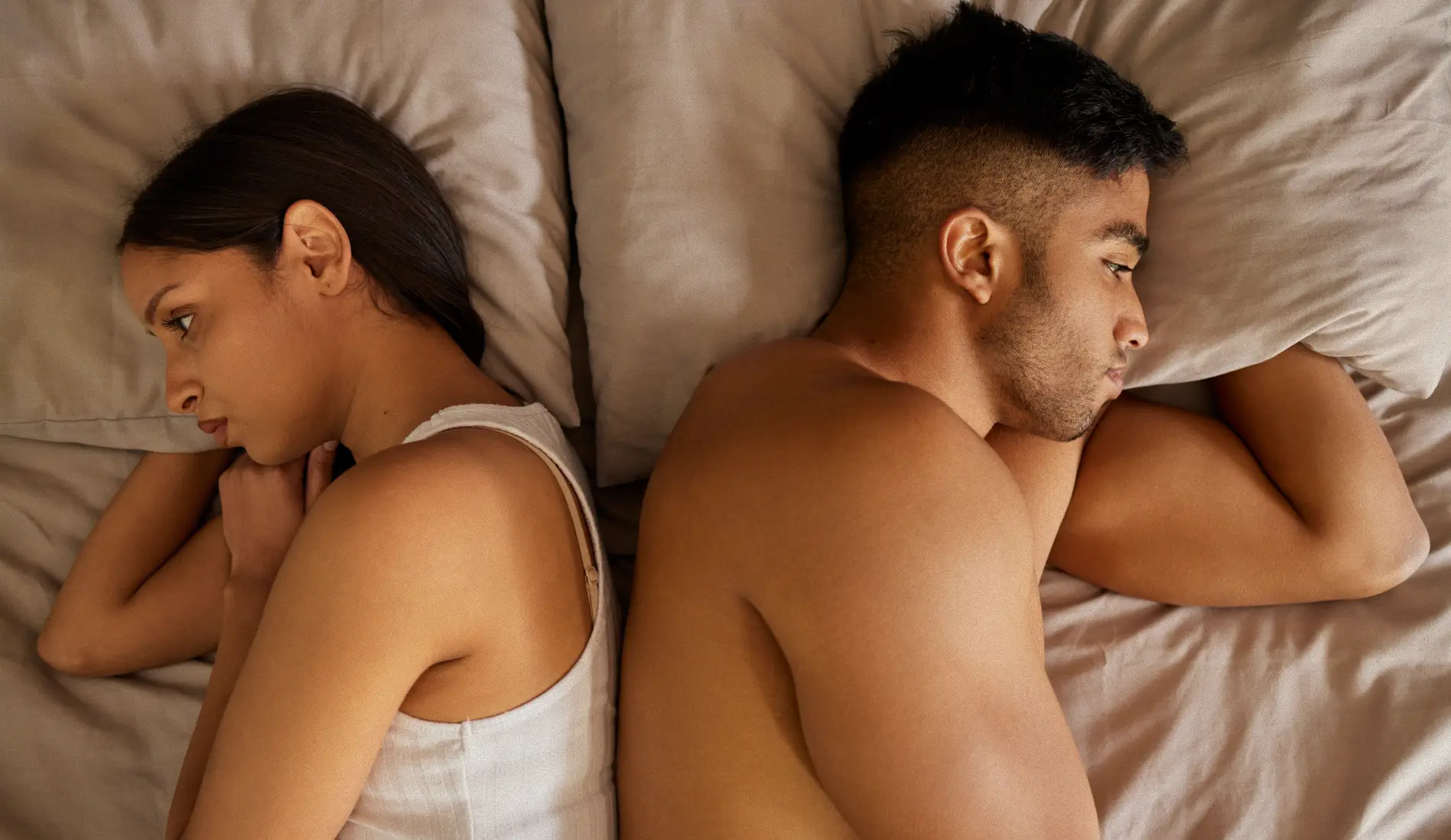 Un couple (homme et femme) allongé, qui se tourne le dos car souffrant de dyspareunie.