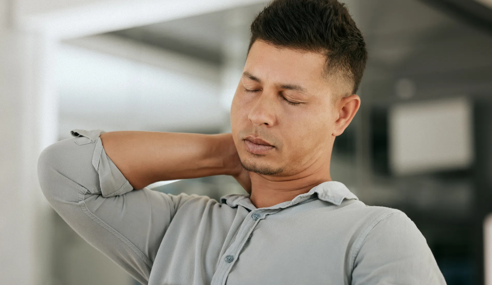 Une personne se touchant son cou douloureux, car elle souffre d'une entorse cervicale.