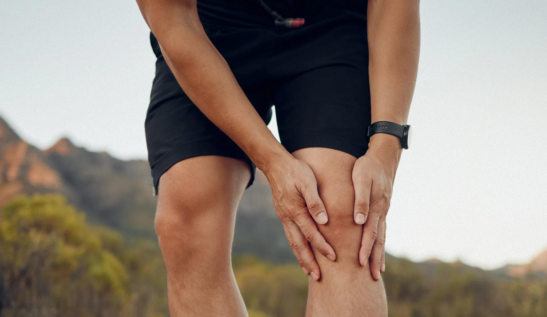Un coureur qui se tient le genou gauche avec ses deux mains car il s'est fat une entorse
