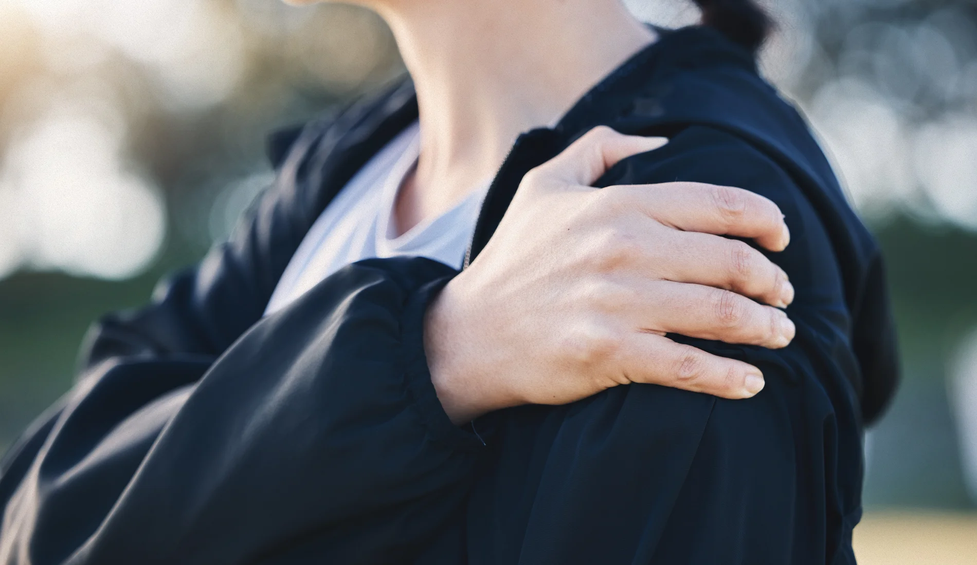 Une personne souffrant de tendinite à l'épaule gauche, se tient celle-ci avec sa main droite.