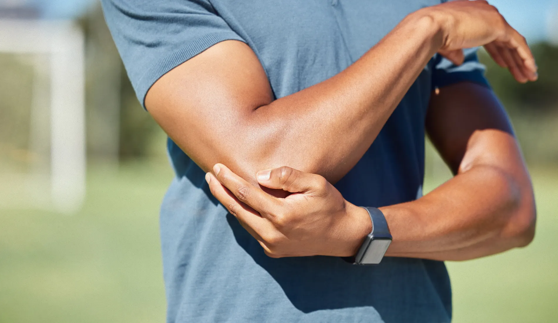 Une personne qui se tient le coude droit car il souffre de tendinopathie