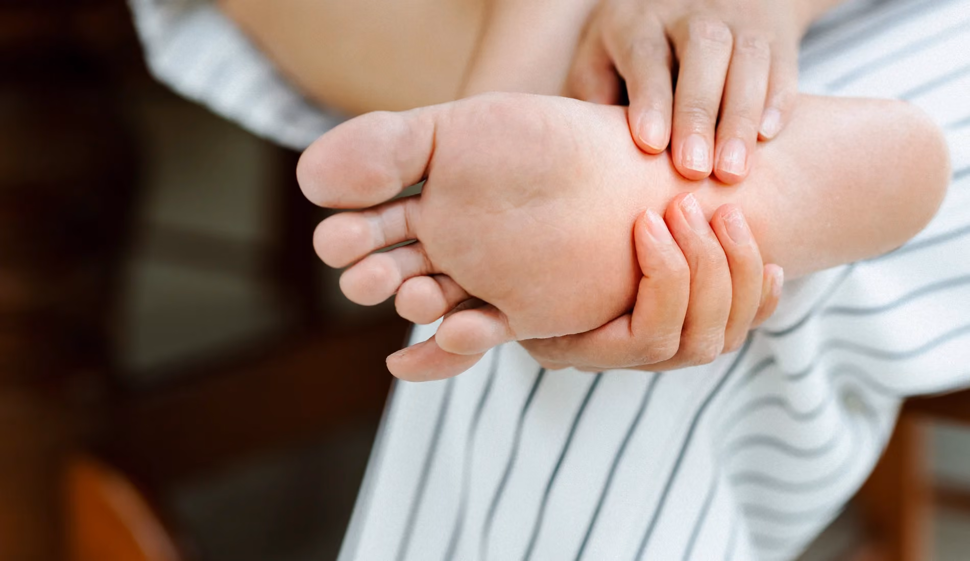 Une personne souffrant de tatalgie, qui se masse le pied.