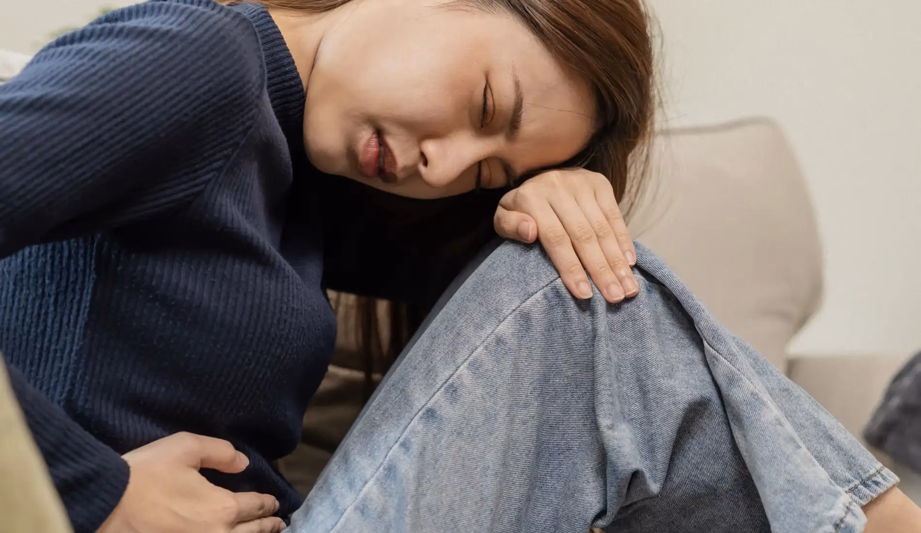 Une jeune femme qui se tord de douleur, car elle souffre de douleurs vaginales.