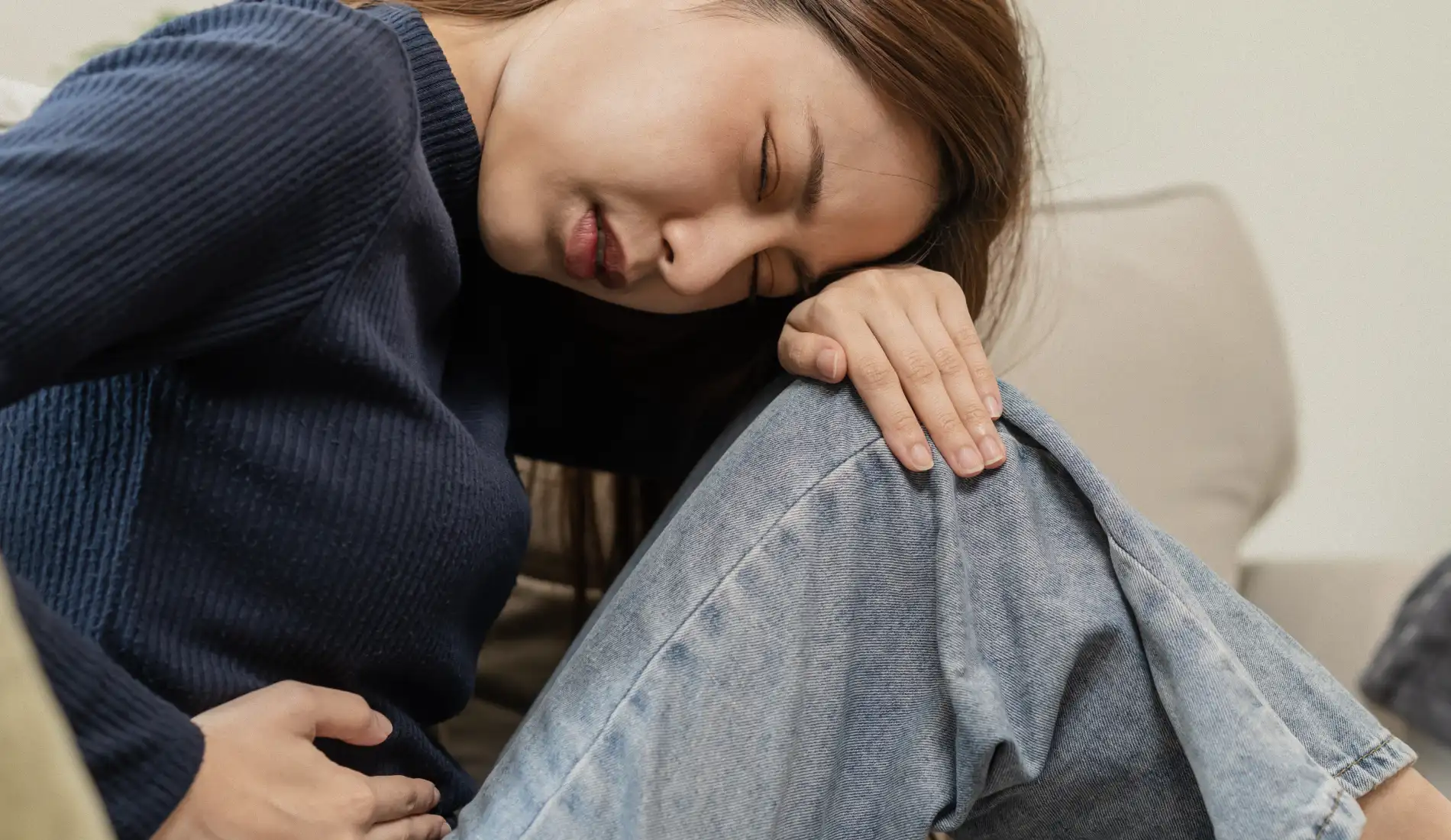 Une jeune femme qui se tord de douleur, car elle souffre de douleurs vaginales.