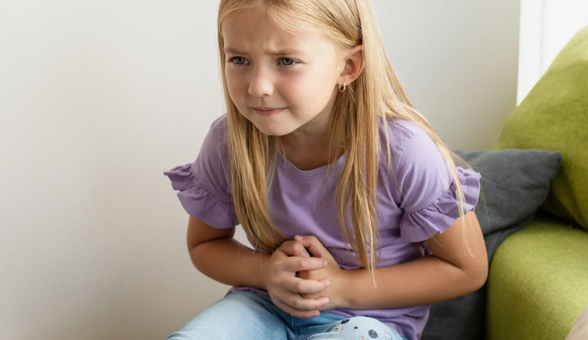 Une enfant qui se plie de douleur car elle a mal au ventre avant l'école.