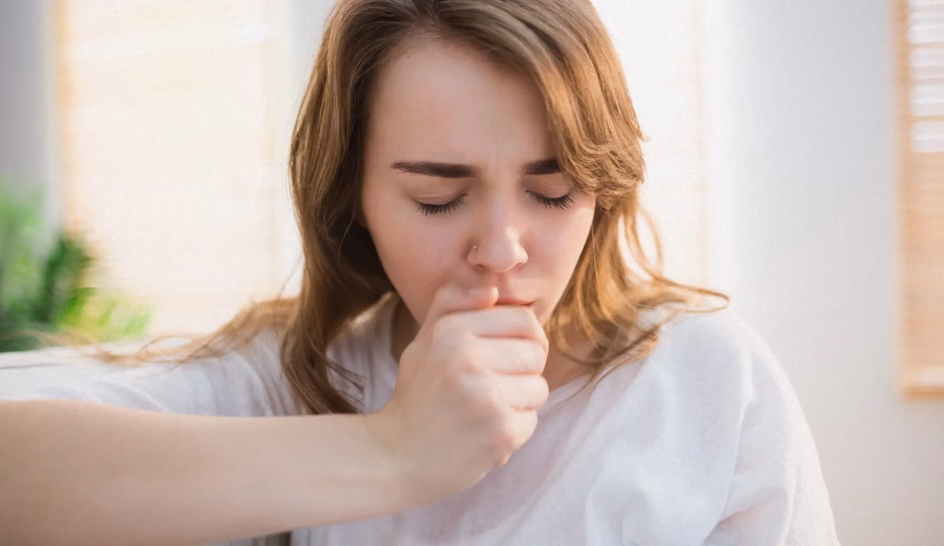 Une personne qui couvre sa bouche pour tousser (toux sèche).