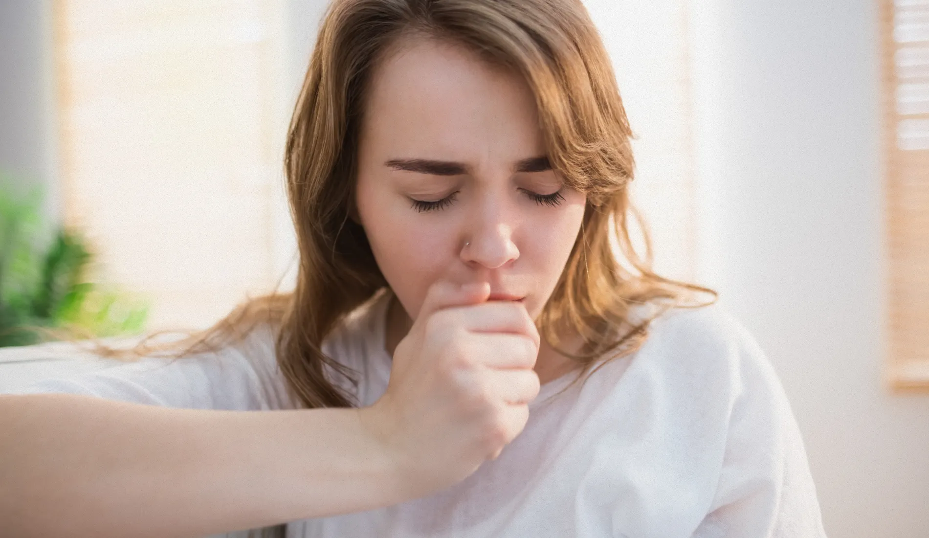 Une personne qui couvre sa bouche pour tousser (toux sèche).