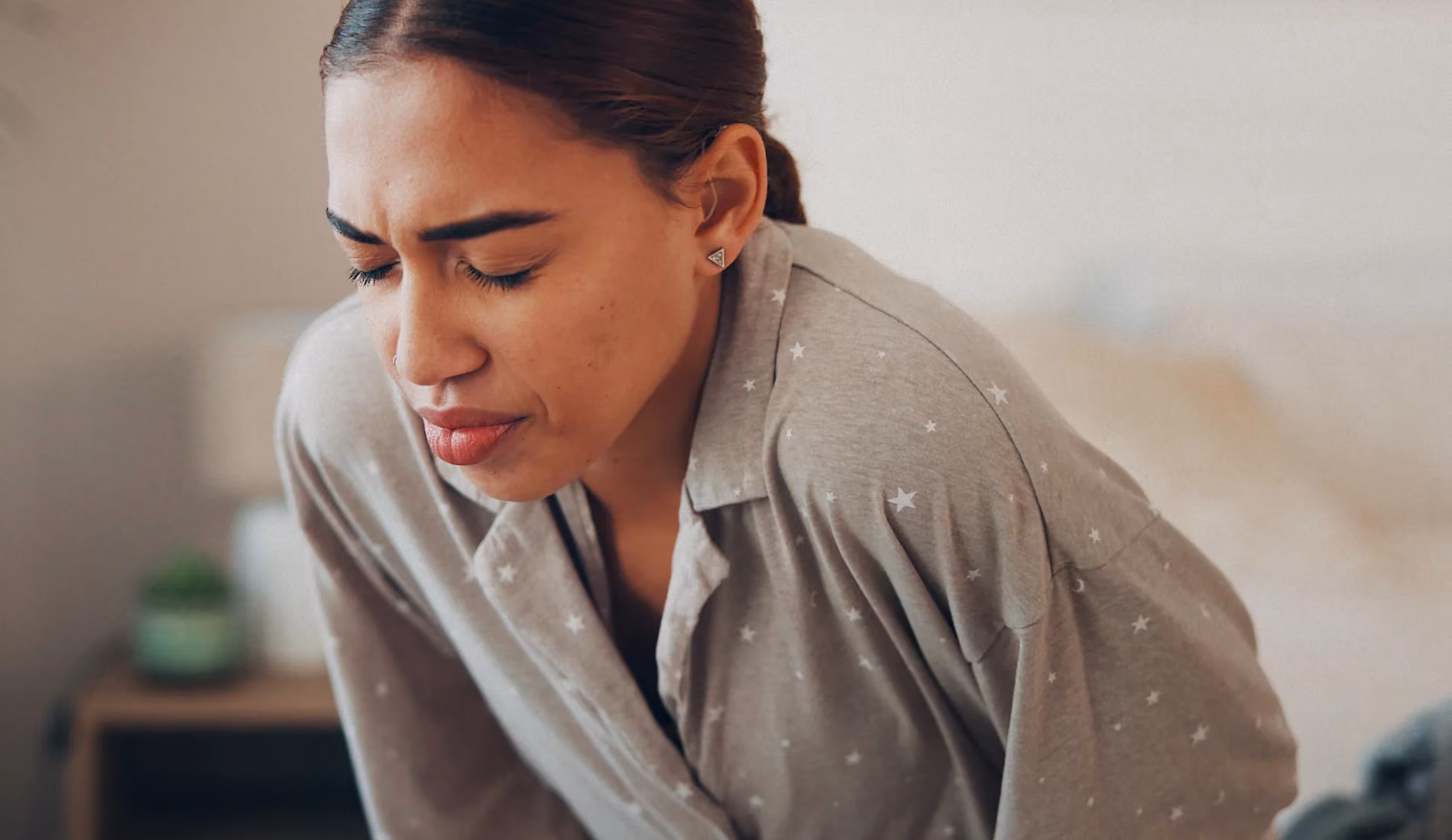 Une jeune dame courbée, car elle cherche une position pour calmer sa douleur aux ovaires
