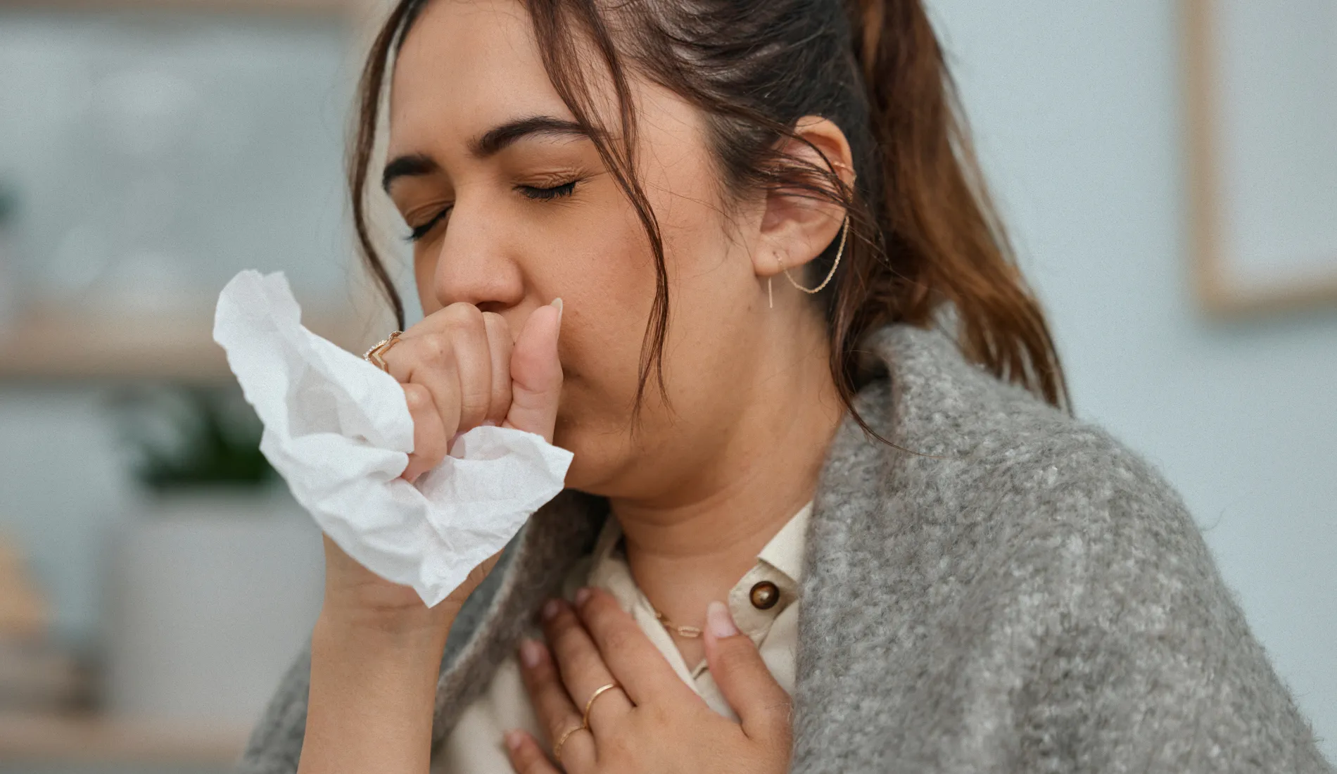Jeune femme portant la main à la bouche en toussant, symptôme typique du bronchospasme lié à un rétrécissement soudain des voies respiratoires