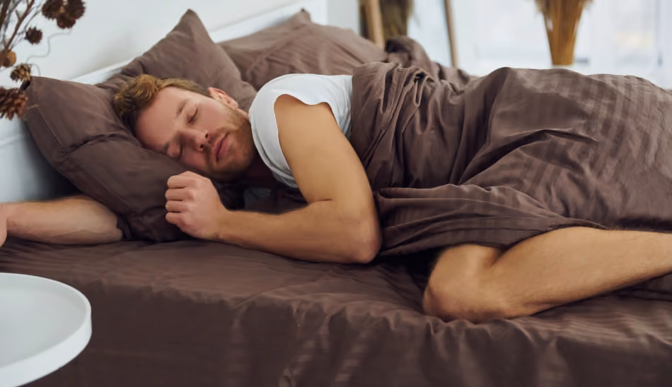 Personne endormie paisiblement dans son lit, illustrant les conditions d'un sommeil réparateur et les bienfaits d'une bonne hygiène de sommeil