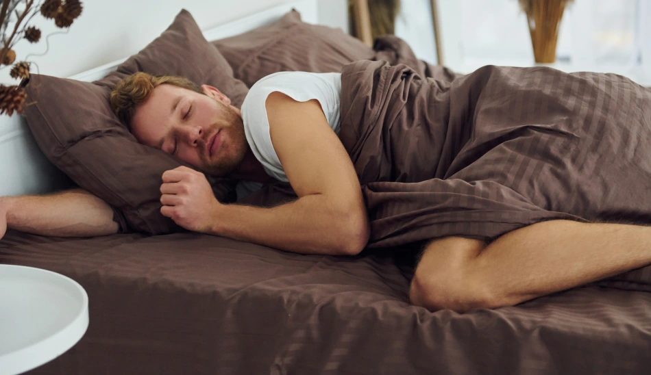 Personne endormie paisiblement dans son lit, illustrant les conditions d'un sommeil réparateur et les bienfaits d'une bonne hygiène de sommeil