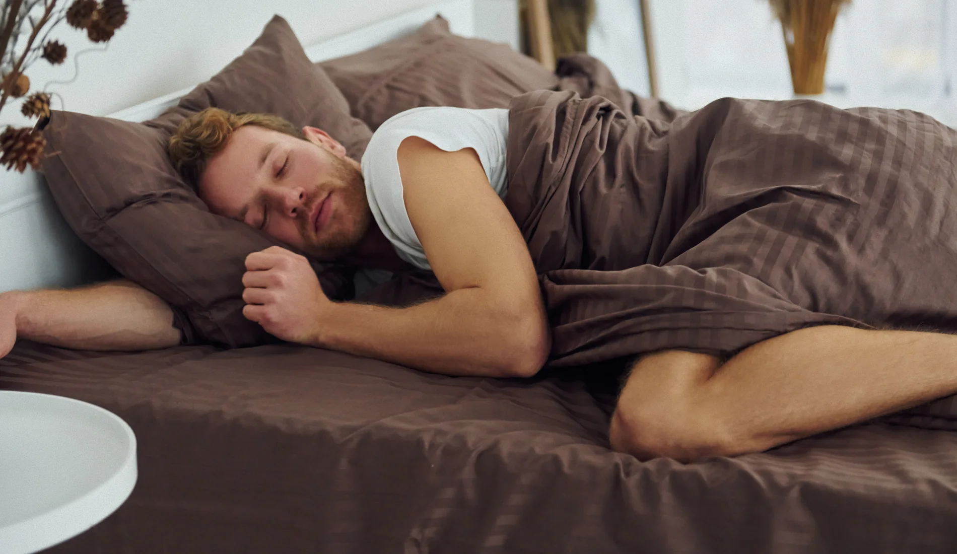 Personne endormie paisiblement dans son lit, illustrant les conditions d'un sommeil réparateur et les bienfaits d'une bonne hygiène de sommeil