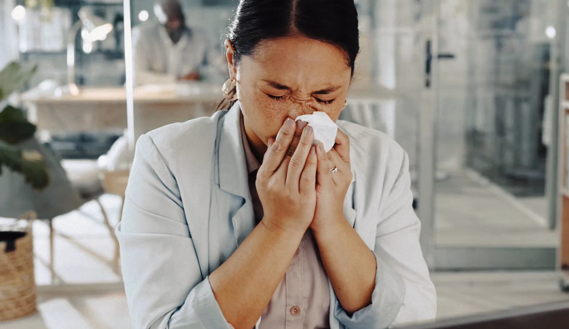 Personne éternuant dans un mouchoir, symptôme typique de l'allergie de saison liée aux pollens de graminées ou d'arbres.