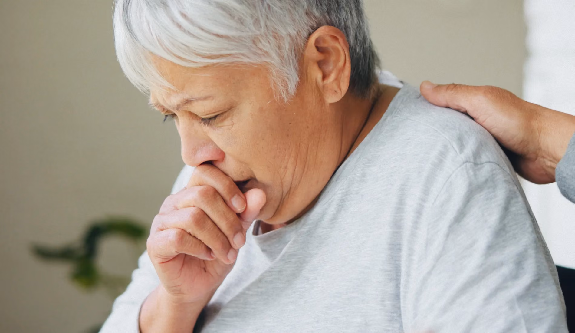 Personne la main sur la bouche en train de tousser, illustrant la toux chronique et la gêne respiratoire caractéristiques de la broncho-pneumopathie chronique obstructive (BPCO)